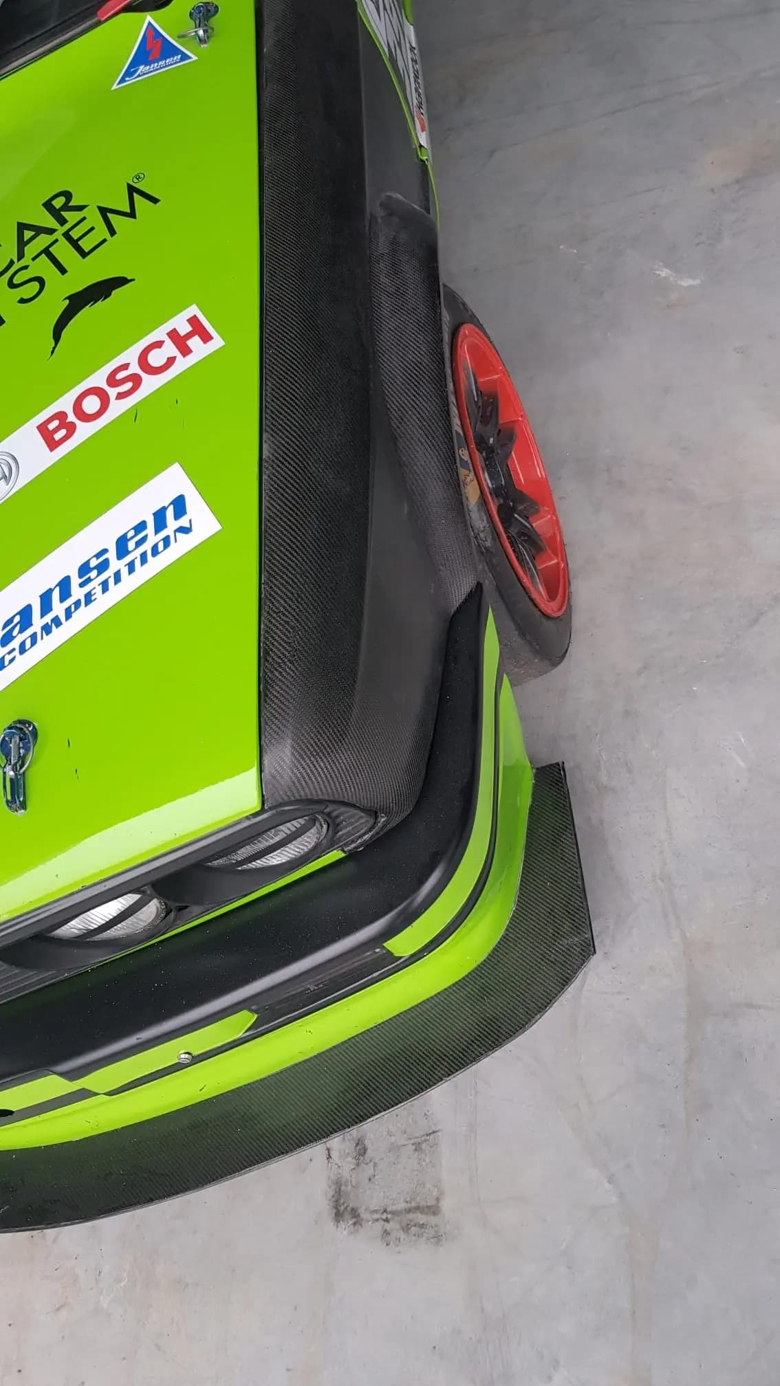Frontansicht eines BMW E30 mit breitem Carbon-Kotflügel, deutliche Radabdeckung und sichtbare Carbonstruktur