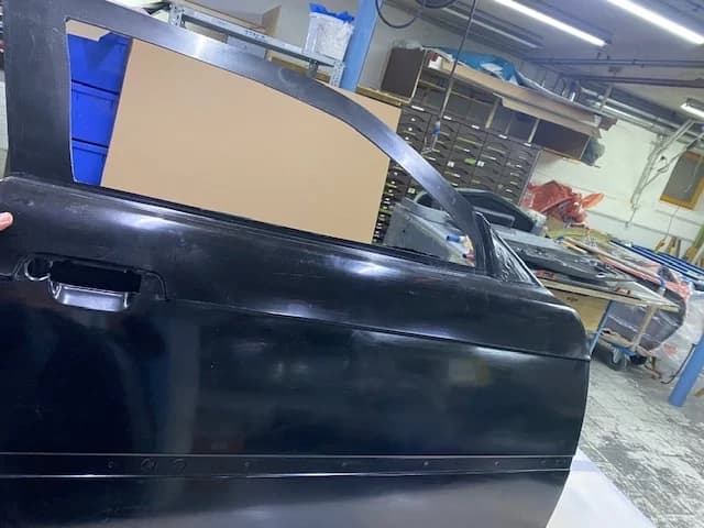 Außenansicht BMW E36 M3 Tür aus Carbon in schwarzer Oberfläche in der Werkstatt