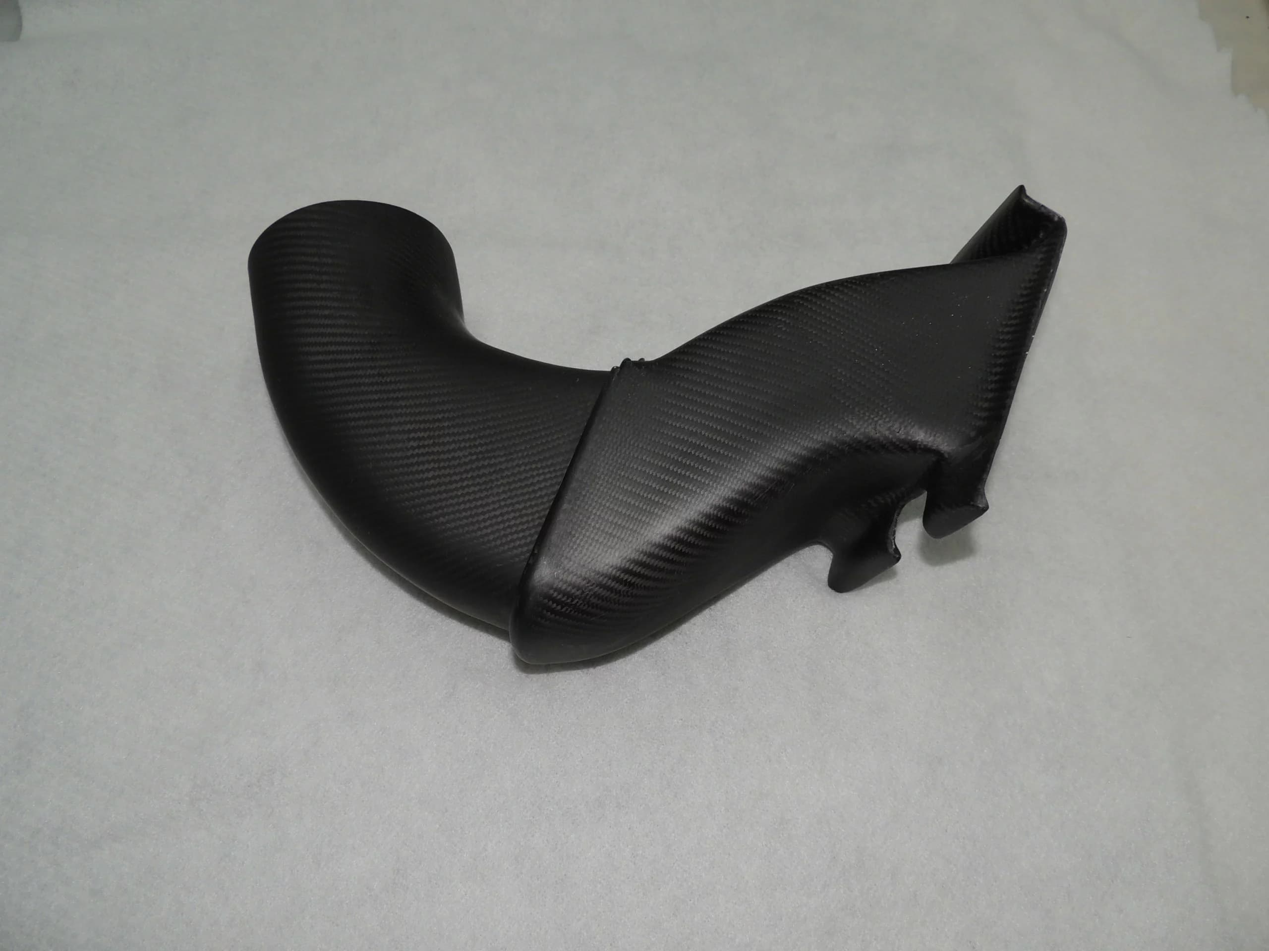 Schrägansicht eines Carbon-Airbox-Luftkanals (Ansaugschnorchel/Siphon) mit geformtem Einlass und gebogener Kanalführung