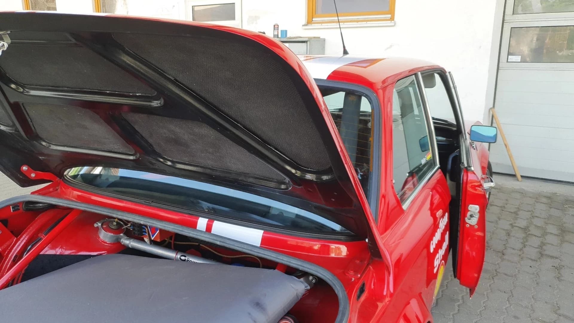 Nahaufnahme des Carbon Kofferraumdeckels vom roten BMW E10 1502-2002 Alpina auf einem Hof