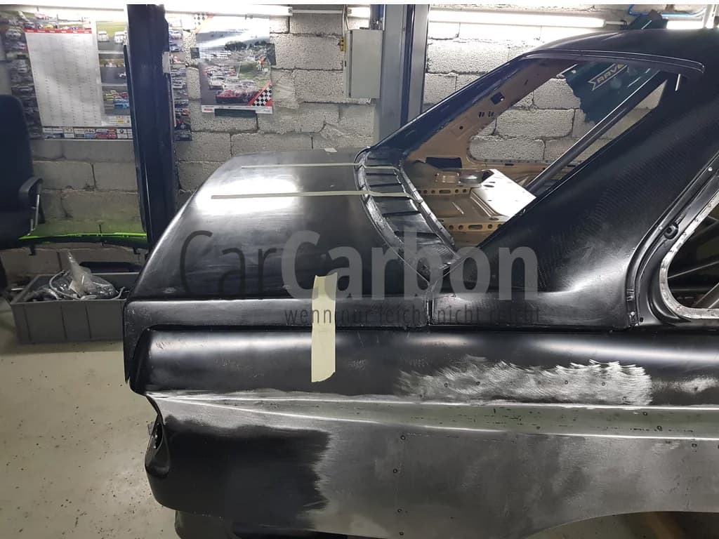 Seitenansicht Heckbereich eines BMW E30 M3 mit montiertem Carbon C-Säulenaufsatz (Sichtcarbon) und vorbereiteter Karosserie, Einbau-/Werkstattaufnahme