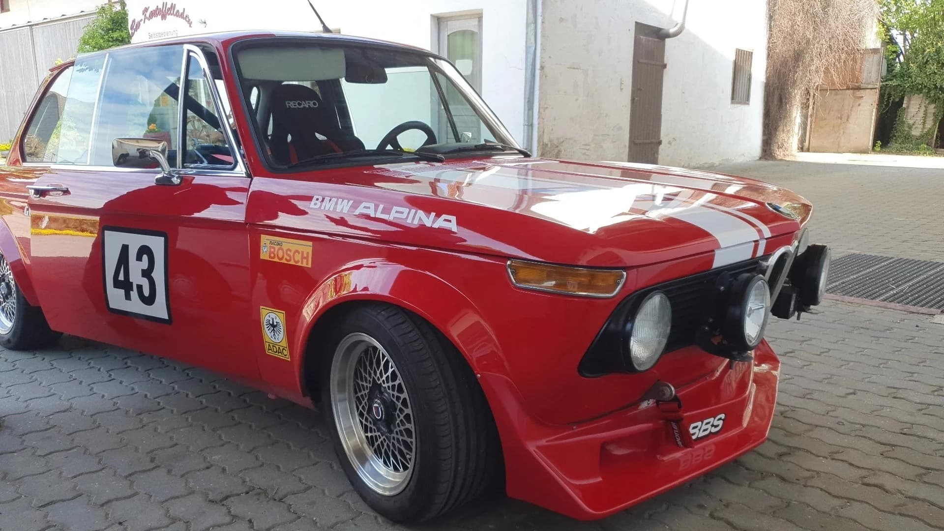 Roter BMW E10 1502-2002 Alpina steht auf einem Hof