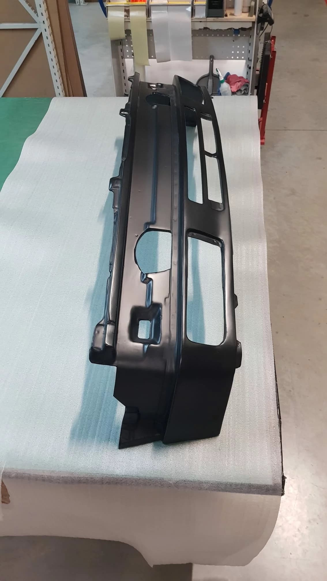 Außenseite des Carbon-Frontblechs für BMW E30, schwarz beschichtet mit Ausschnitten und Kanten, auf Arbeitstisch liegend.