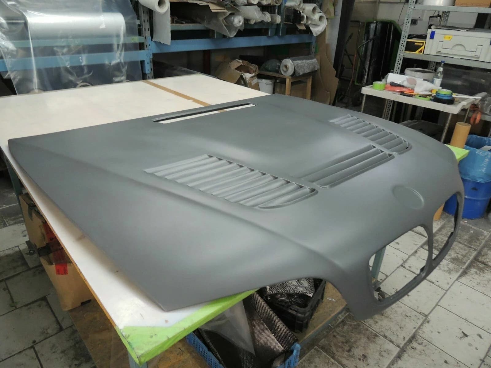Schrägansicht der Carbon Motorhaube BMW E46 M3 GTR, Rohteil vor der Lackierung in Werkstattumgebung