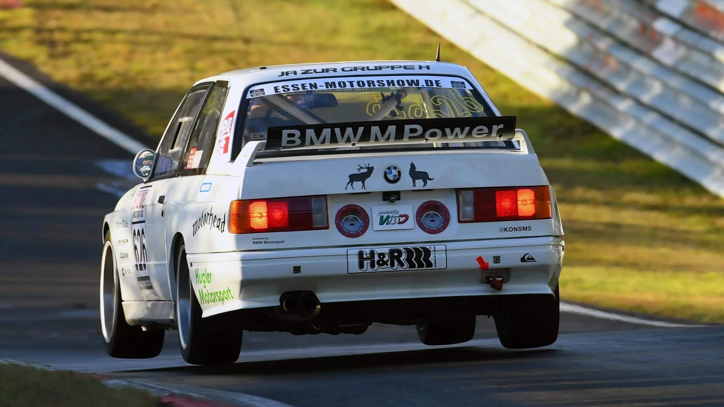 BMW E30 M3 Rennfahrzeug mit montiertem Carbon-Kofferraumdeckel auf der Rennstrecke, Heckansicht