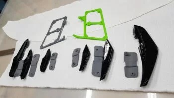 VFL Canards für Audi TT, Set mit schwarzen Canards, grauen Haltern und grünen Montagehilfen auf weißer Unterlage