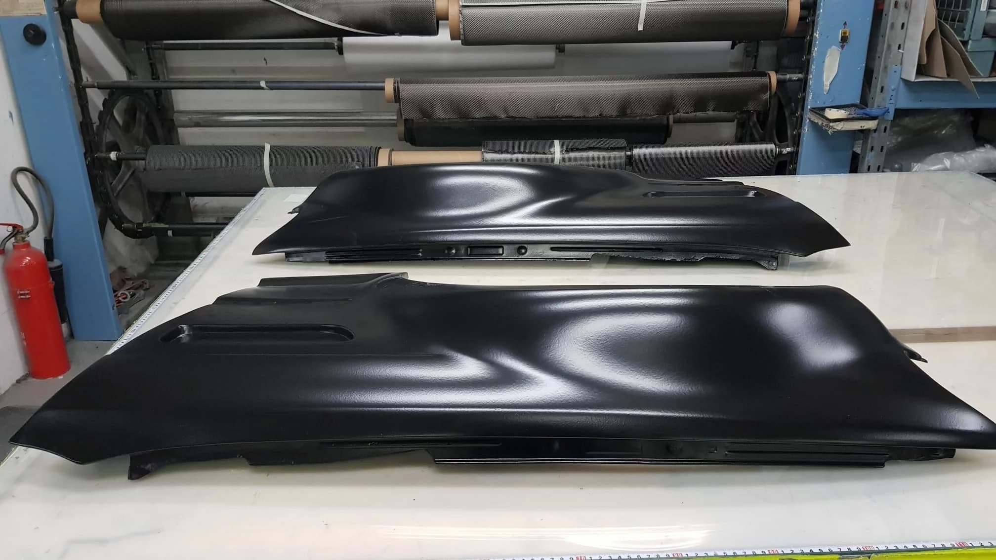 Zwei Carbon-Kotflügel BMW E46 M3 nebeneinander auf Arbeitstisch, Rohzustand