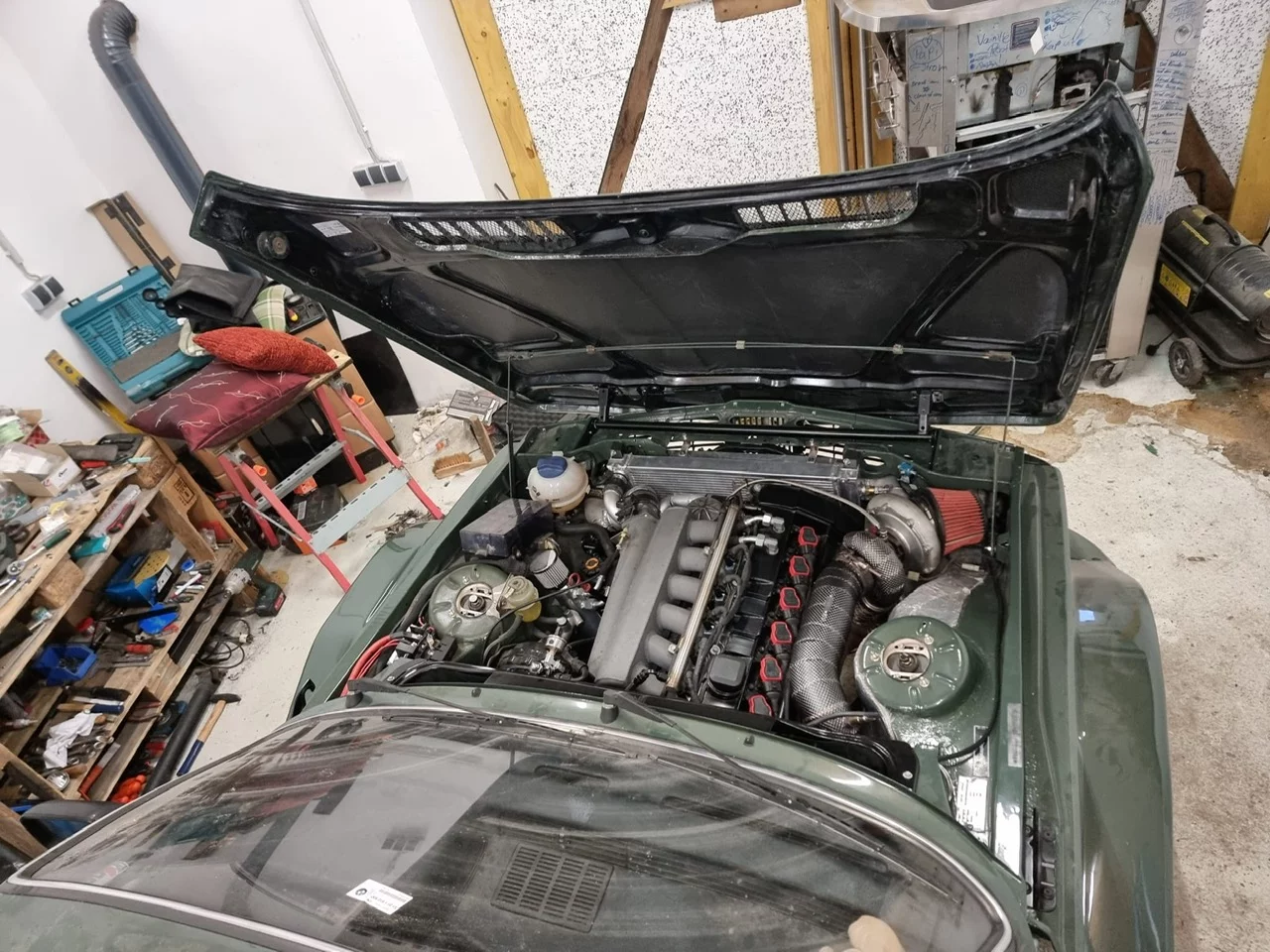 Grüner BMW E21 mit geöffneter Carbon Motorhaube und Blick auf den Motor in einer Werkstatt
