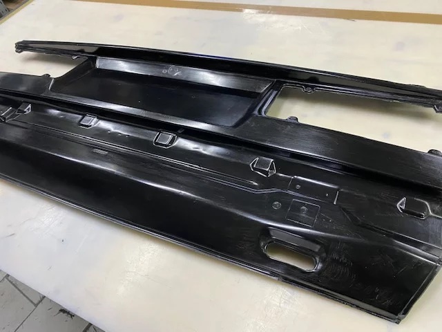 Carbon-Heckblech von hinten mit geformten Kanten und Öffnungen, Bauteilansicht auf Werkbank.