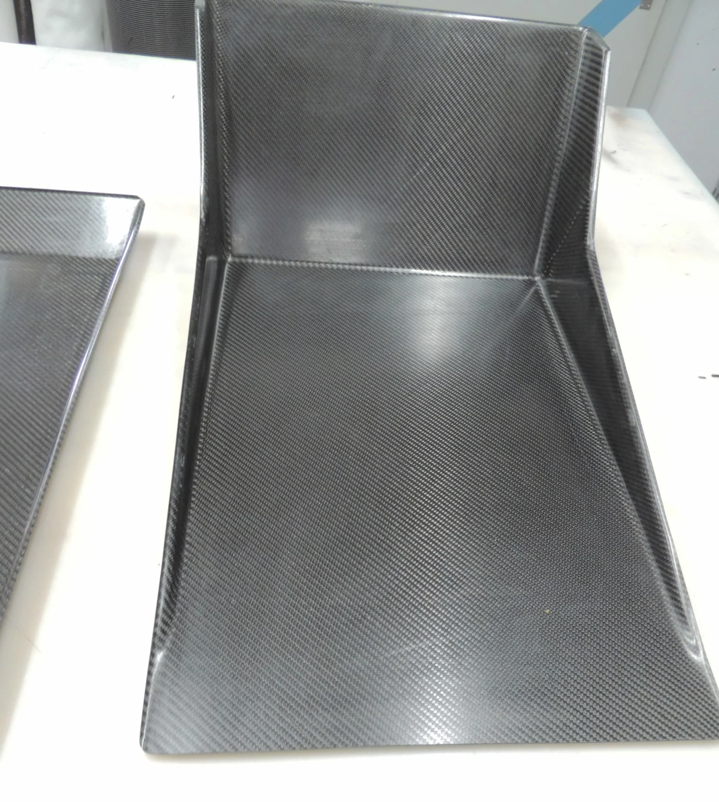 Detailansicht der Carbon Fußraumwanne mit hoher Rückwand und sauber laminierten Kanten, glänzendes Finish.