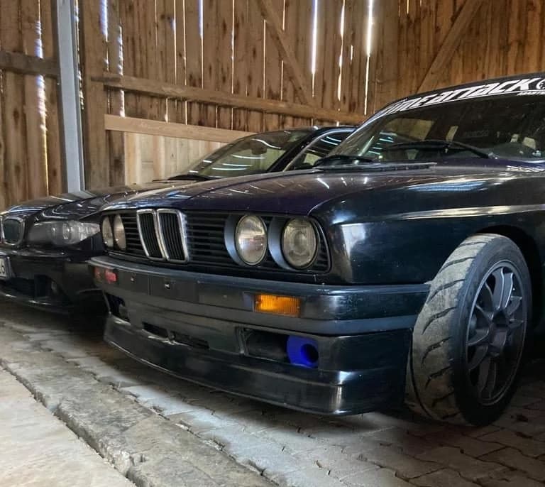 BMW E30 mit montiertem schwarzem Alpina-Style Frontansatz, tiefe Frontansicht in Garage/Scheune