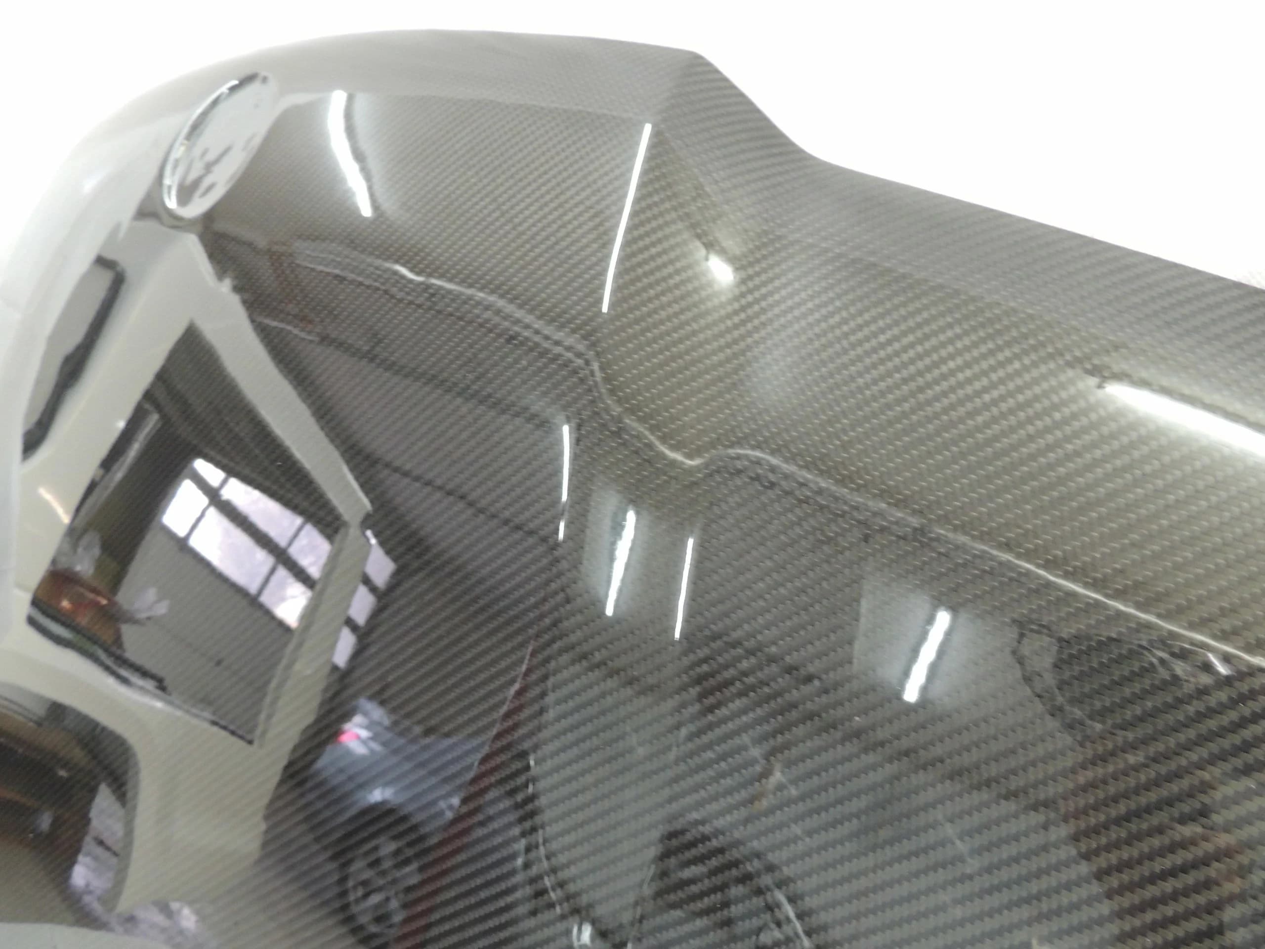 Carbon-Motorhaube Nahaufnahme – Carbon-Gewebe und Klarlack-Finish mit Lichtreflexionen