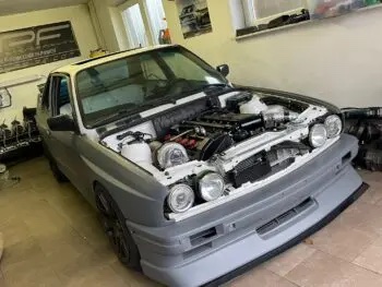 BMW E30 ohne Motorhaube in der Werkstatt von vorne mit Blick auf den Frontspoiler Cecetto