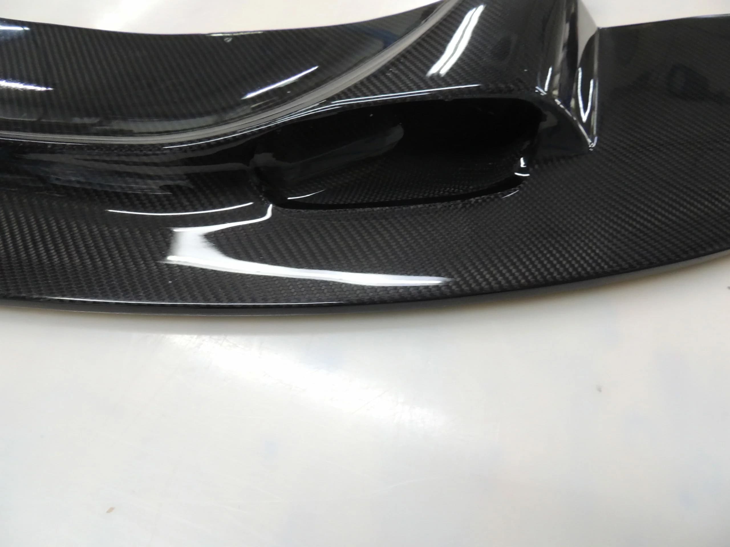 Detailansicht der Carbon-Frontlippe mit glänzender Oberfläche und Luftkanal