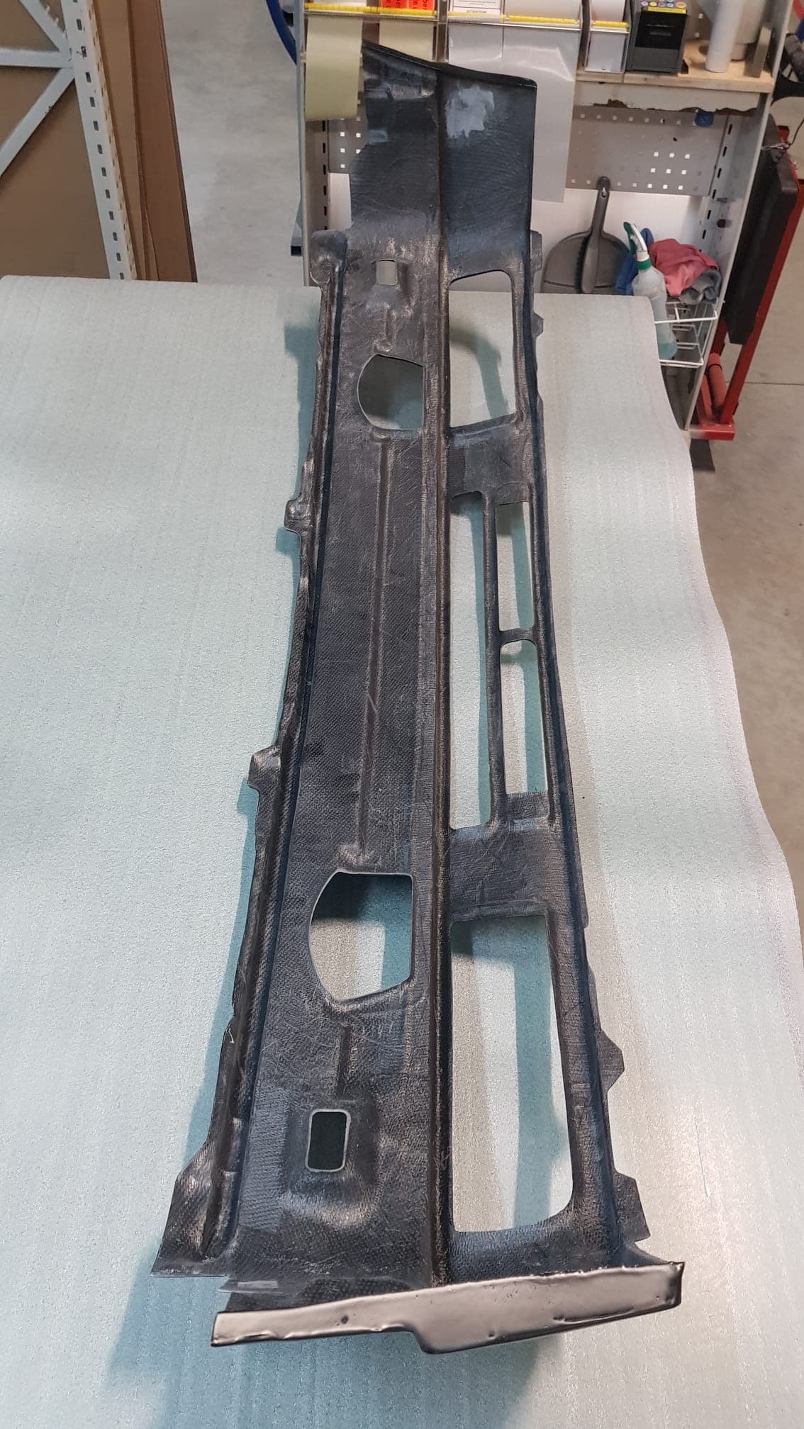 Innenseite des Carbon-Frontblechs für BMW E30 mit strukturierten Verstärkungen und Montageöffnungen, Werkstattumgebung.