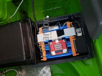 Starterbatterie im Fahrzeug verbaut, geöffneter Batteriekasten mit sichtbaren Modulen und Verkabelung