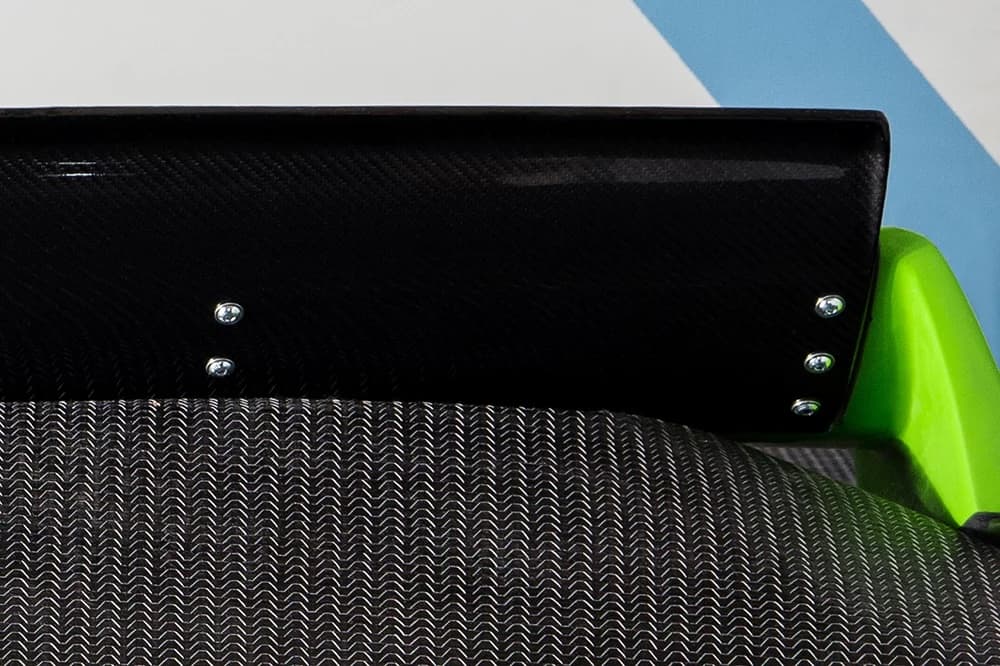Detailaufnahme: Carbon-Flügelelement mit Verschraubung auf grünem Spoilerfuß.