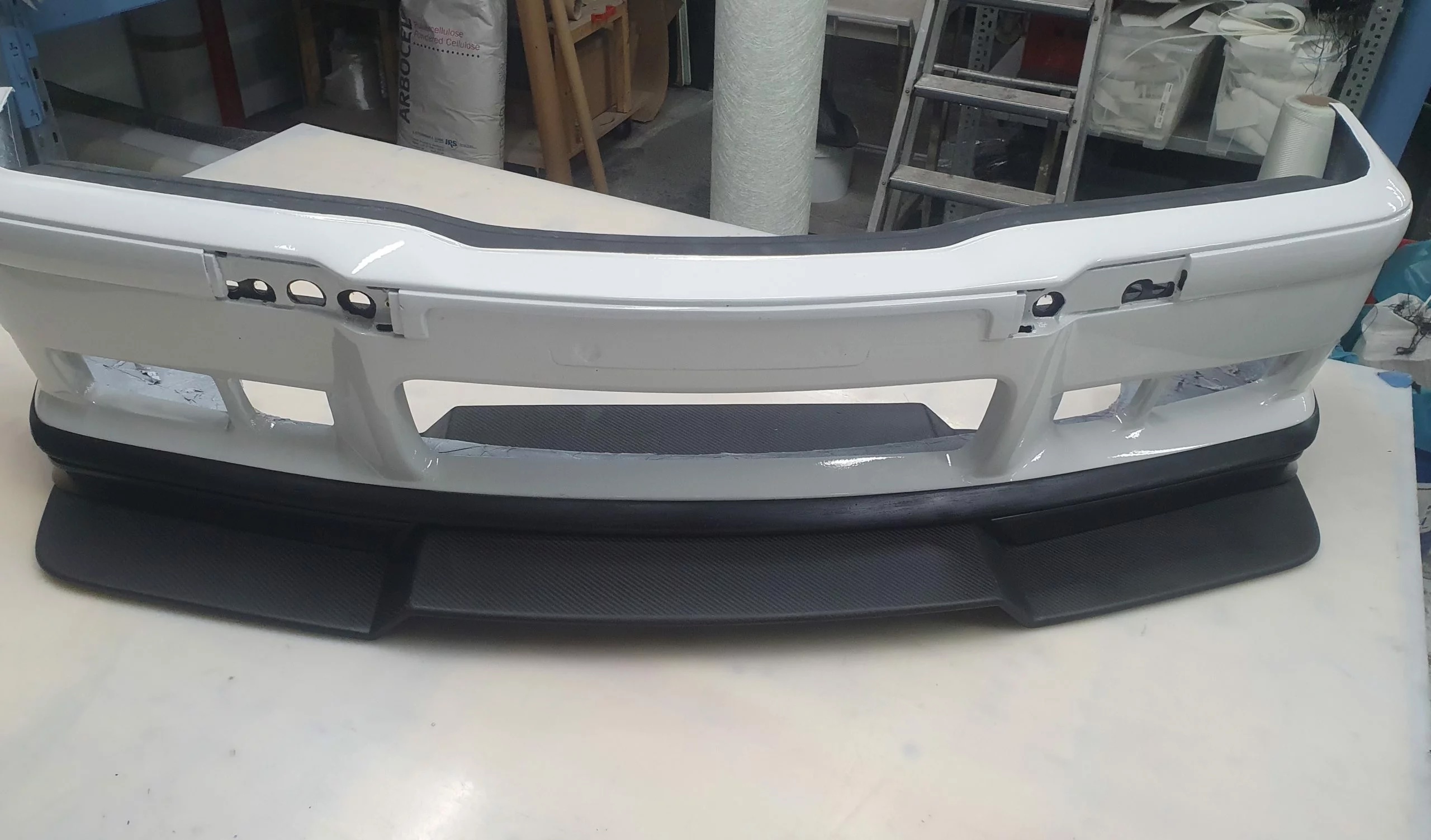 BMW E36 M3 Frontstoßstange mit Carbon-Frontlippe auf Arbeitstisch, unlackierter Stoßfänger